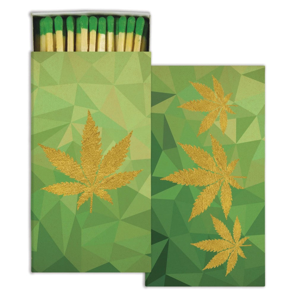 Green matchbox with gold leaves on a geometric background.
