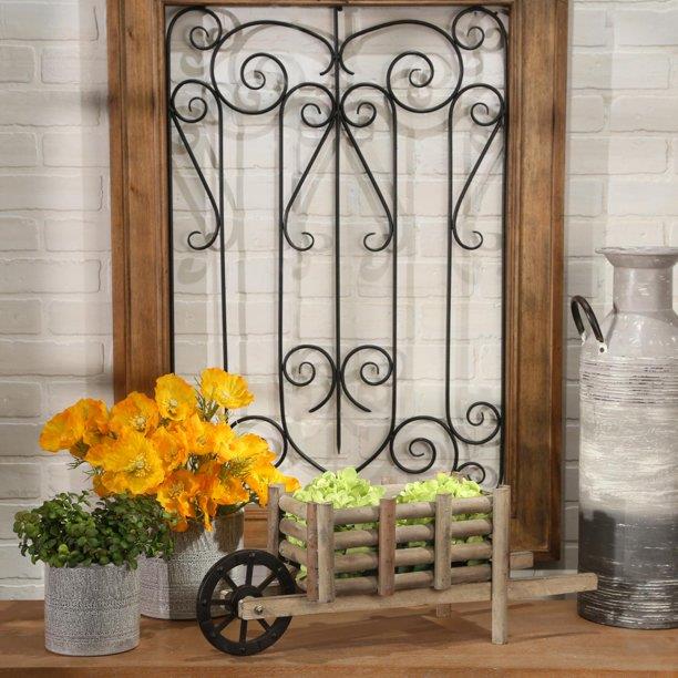 Rustic decor with flowers, plants, a wooden cart, and wrought iron wall art.
