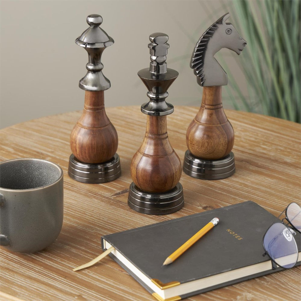 Wooden chess pieces and a mug on a table with a notebook and pencil.