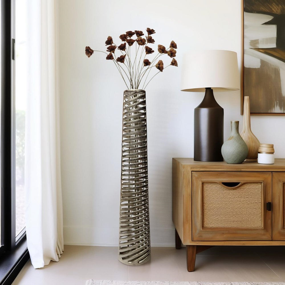 Tall vase with dried flowers beside a wooden console and lamp in a modern room.