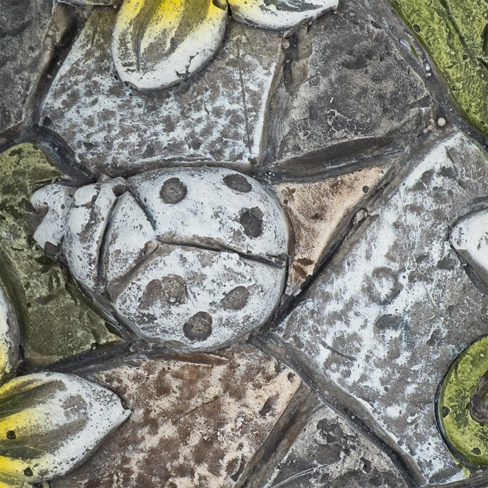 Stone carving of a ladybug surrounded by leaves.