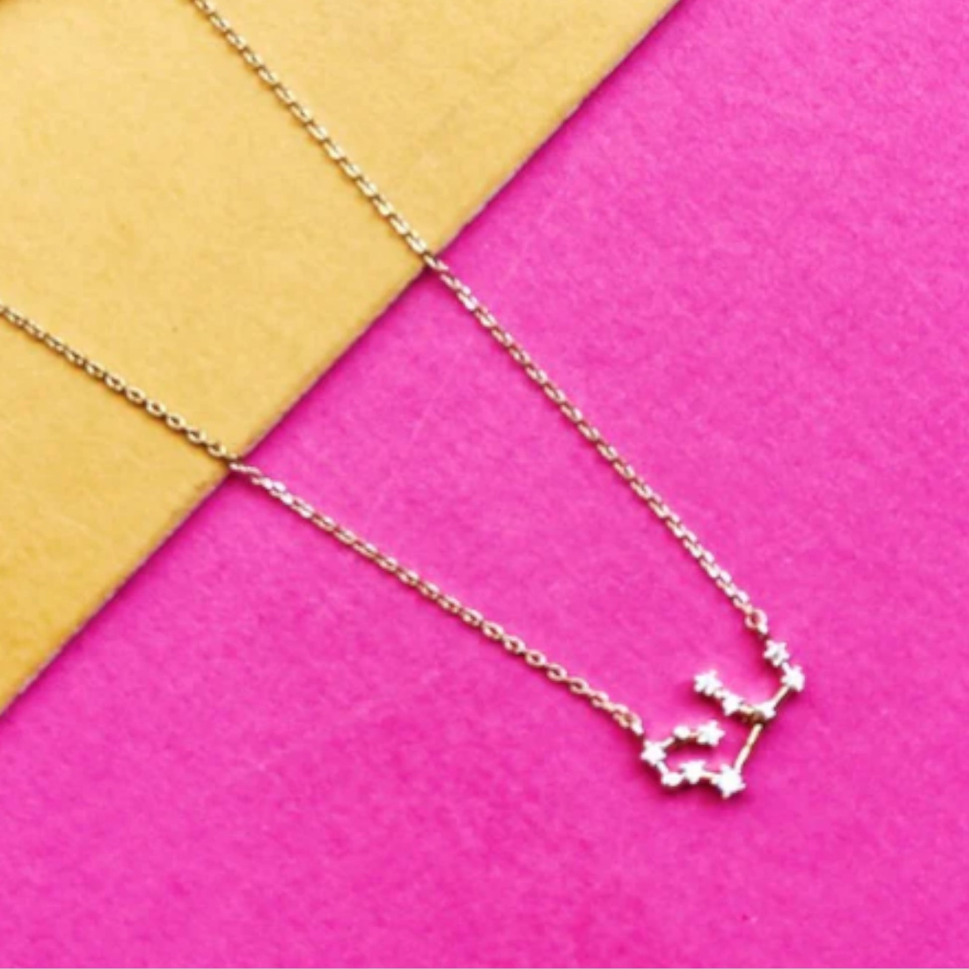 Constellation necklace on pink and yellow background.