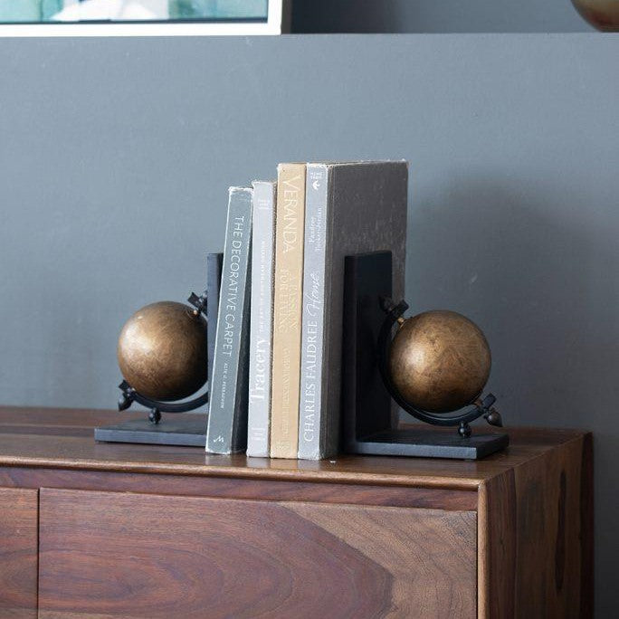 Books with globe bookends on a wooden shelf.