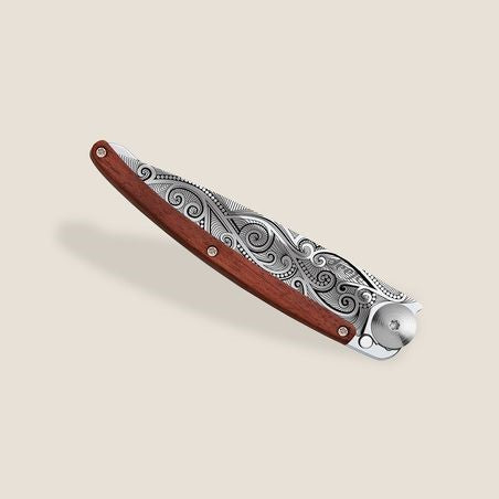 Ornate folding knife with carved wooden handle and intricate metal design.