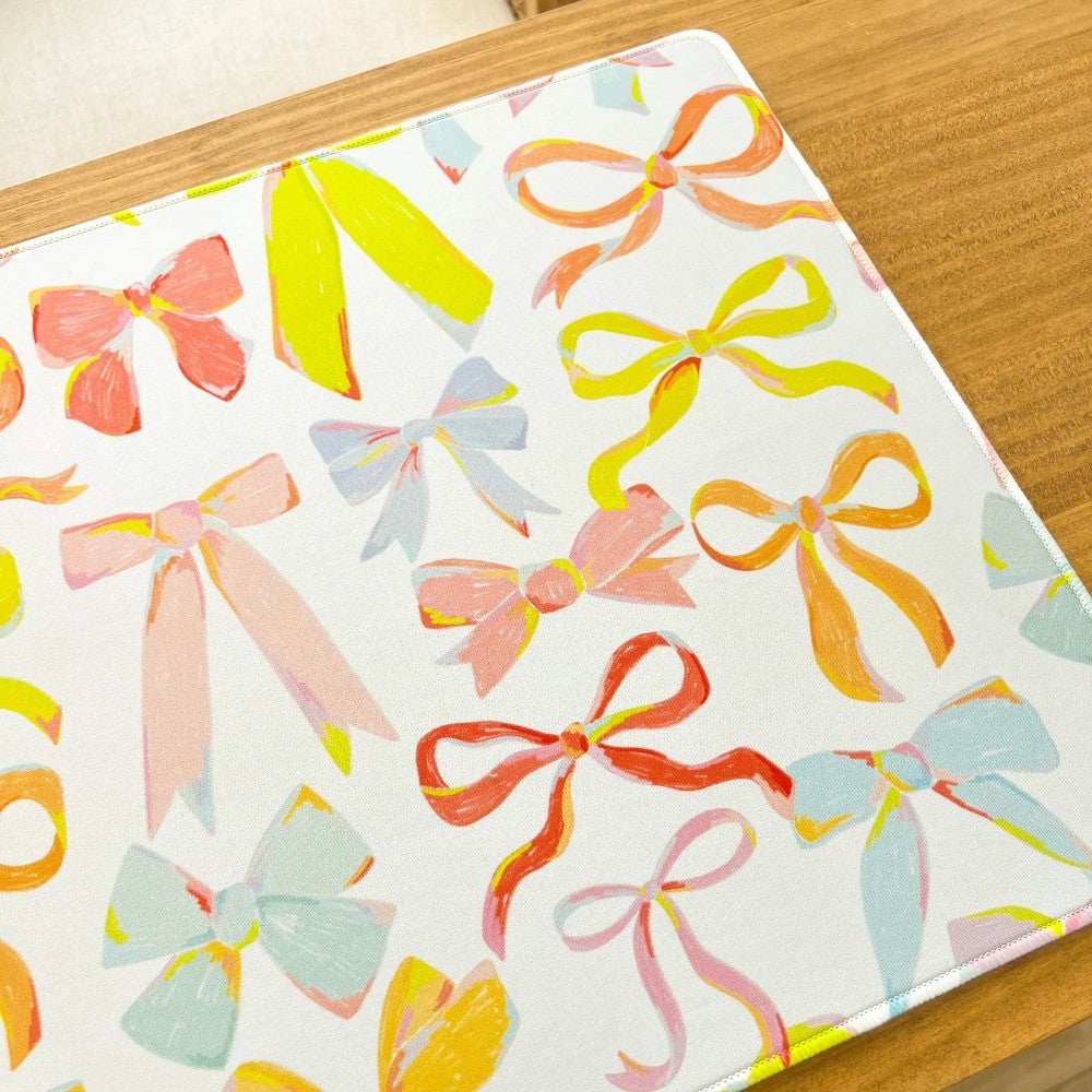 Colorful bows printed on a white fabric with a wooden background.
