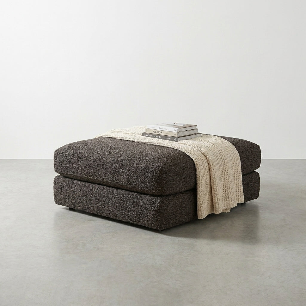 Dark ottoman with blanket and books in a minimalist room.