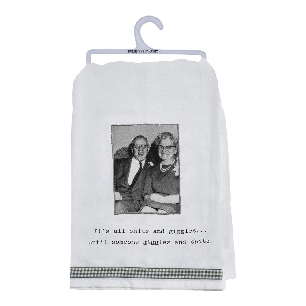 Elderly couple photo on a towel with humorous caption, hanging on a white hanger.