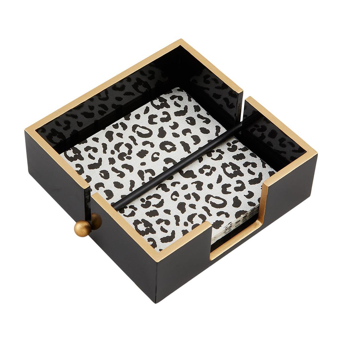 Black napkin holder with leopard-print napkins and gold accents.