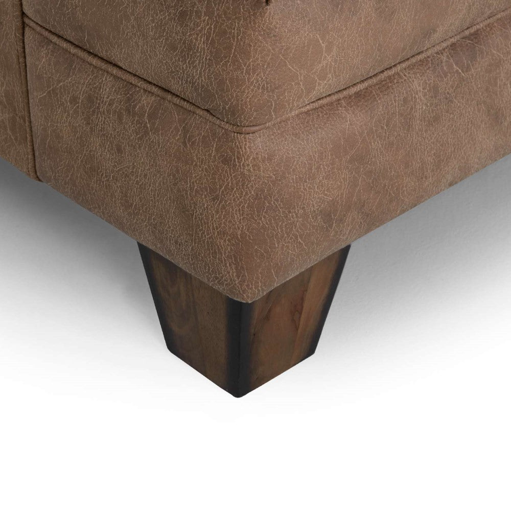 Brown sofa corner with textured upholstery and dark wooden leg.
