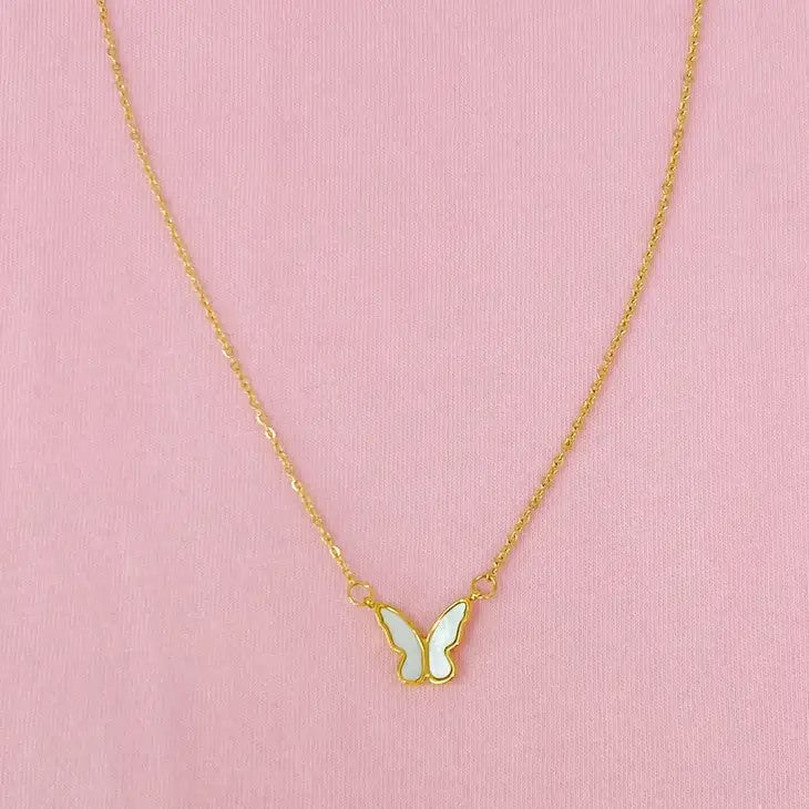 Gold chain with butterfly pendant on pink background.