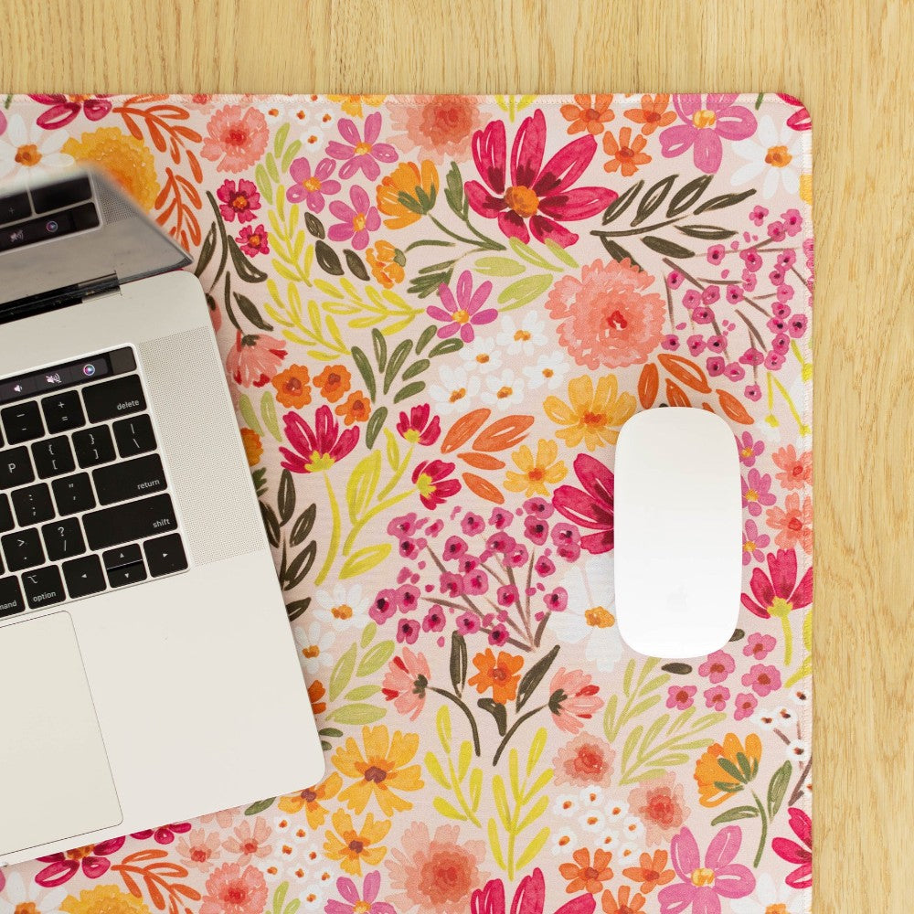 Laptop and mouse on a colorful floral desk mat.