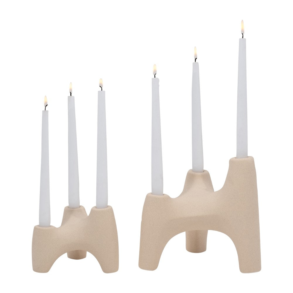 Modern candlesticks with tall white candles lit on beige holders.