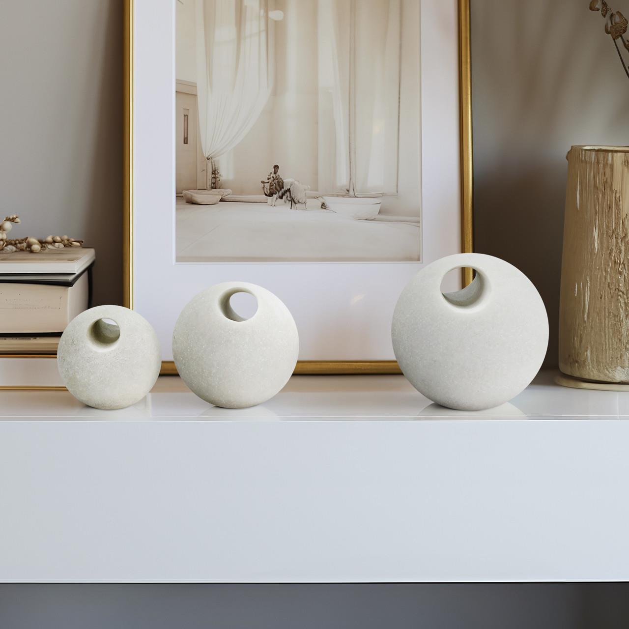 Three round vases on a shelf with a framed photo in the background.