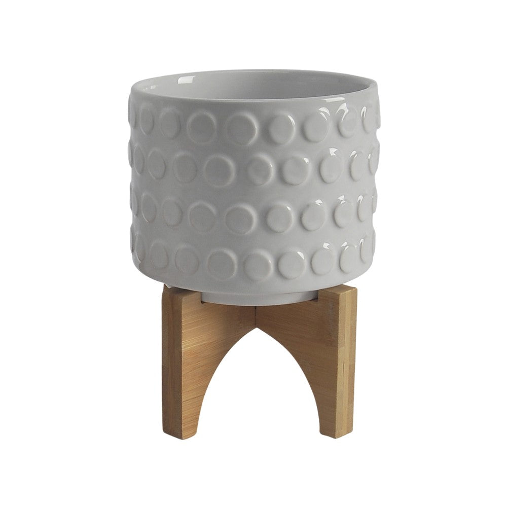 White textured pot on wooden stand.