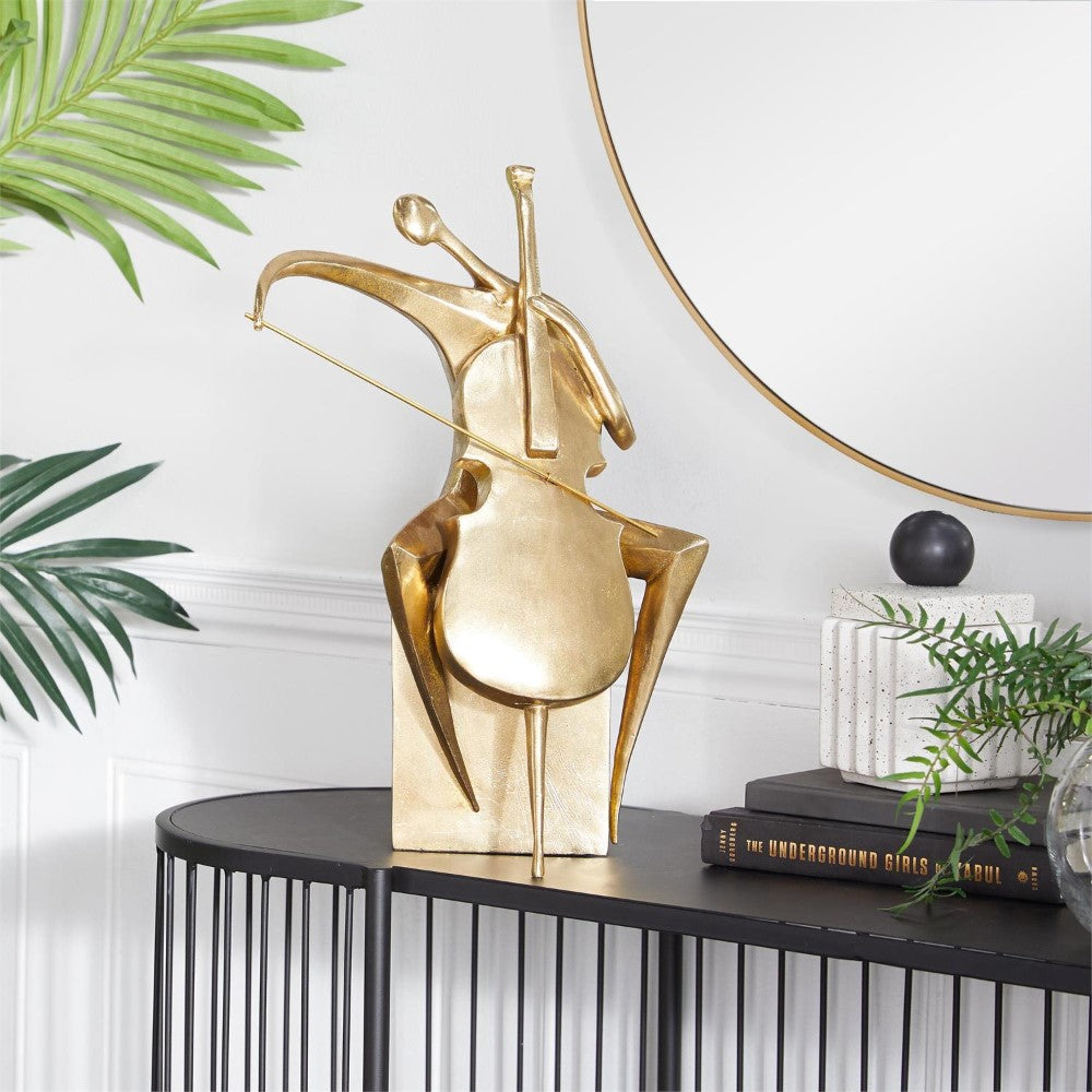 Golden abstract cellist sculpture on a black console table.