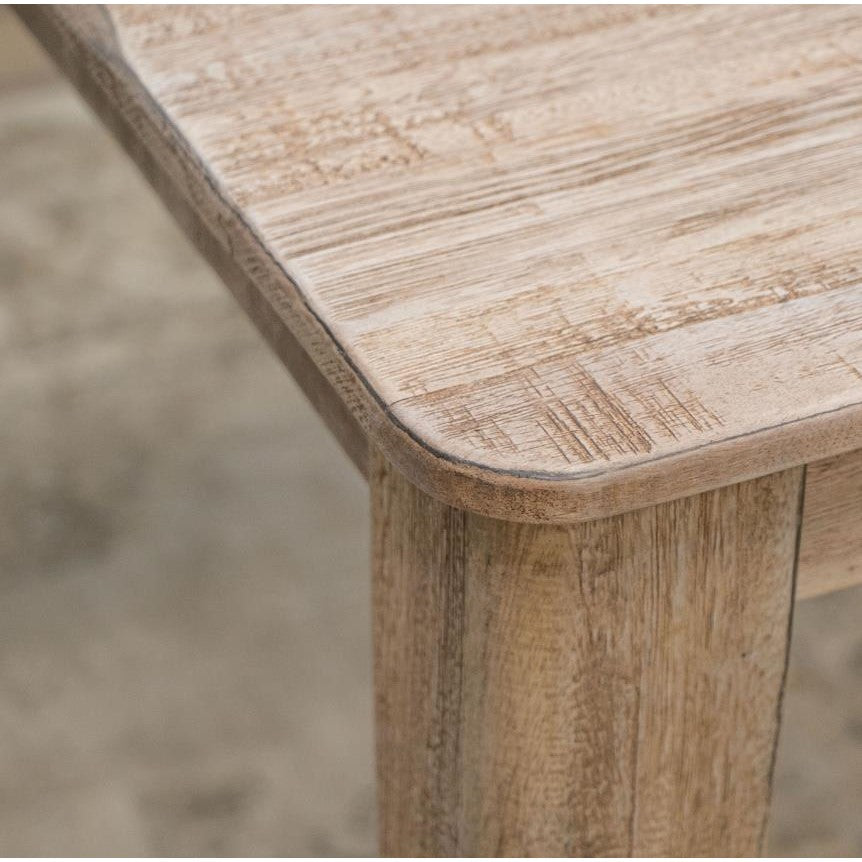 Close-up of a wooden table corner on a textured surface.