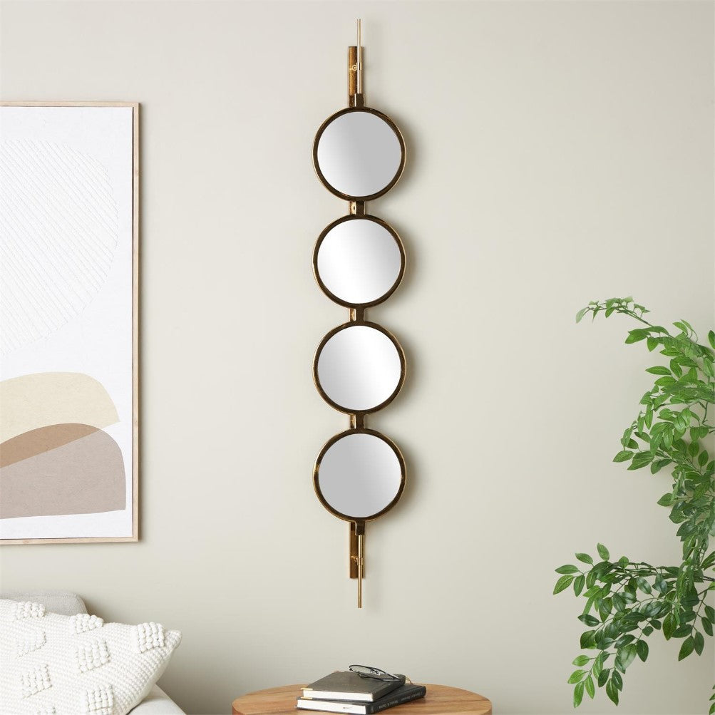 Round mirrors vertically arranged on a wall with plants and artwork nearby.