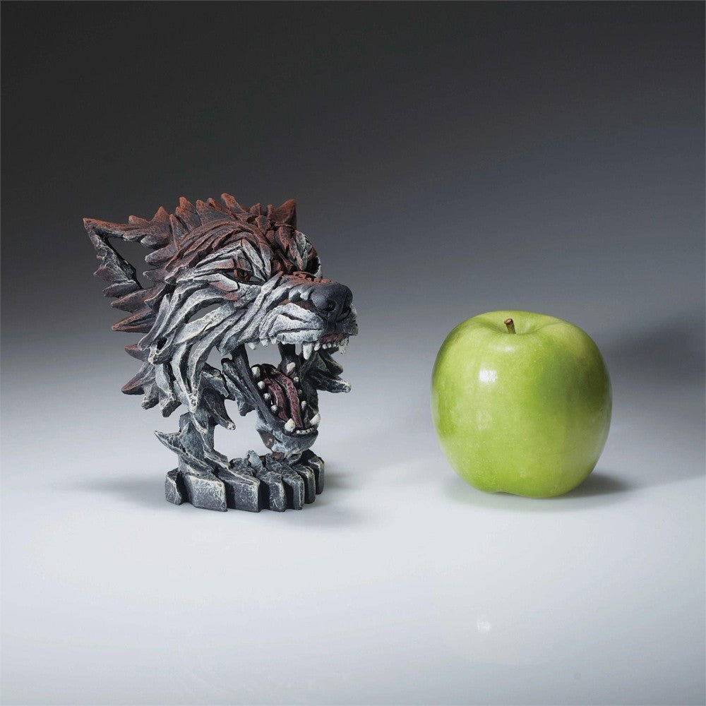 Wolf sculpture and green apple on a white surface.