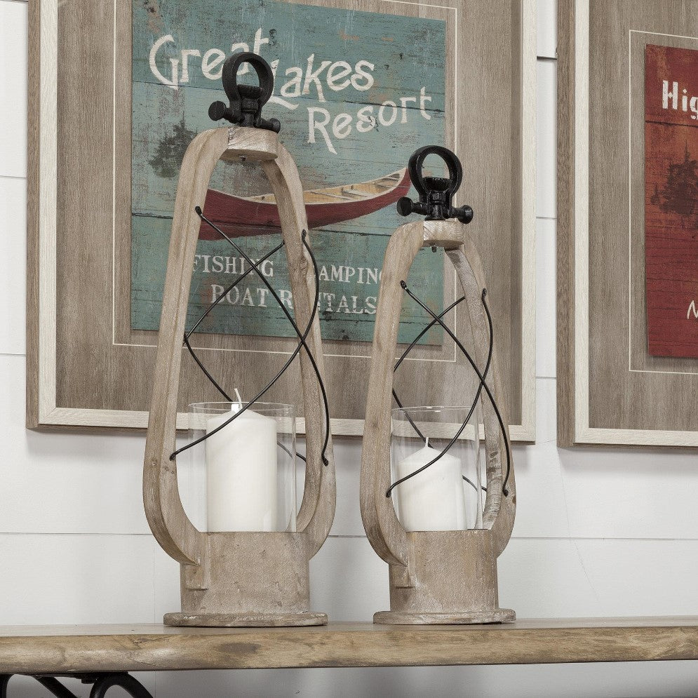 Wooden lanterns on a shelf with rustic wall art.