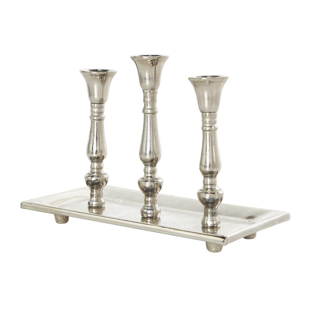 Shiny silver metal three-candle holder on a rectangular base.