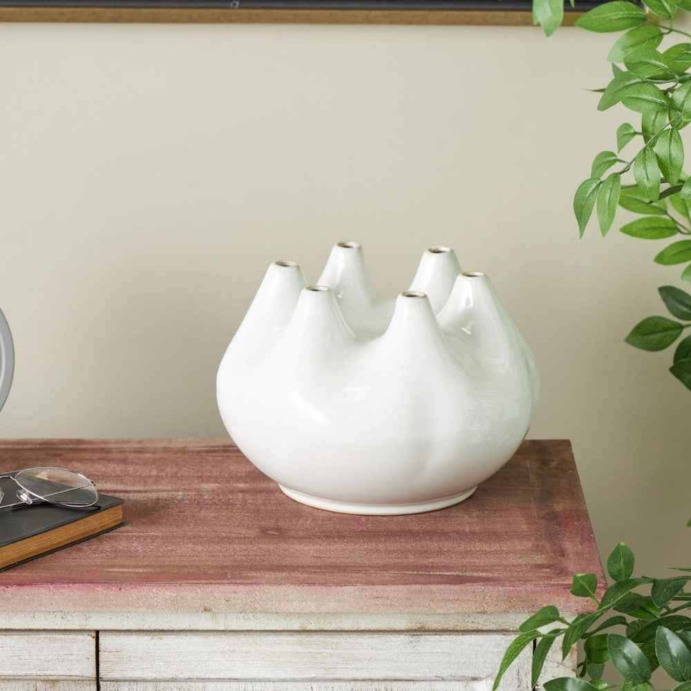 Unique white vase with multiple openings on a wooden table.