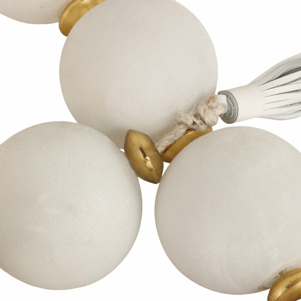 White beads with gold accents and tassel on a string.
