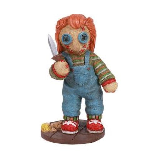 Voodoo doll with orange hair and overalls holding a knife.