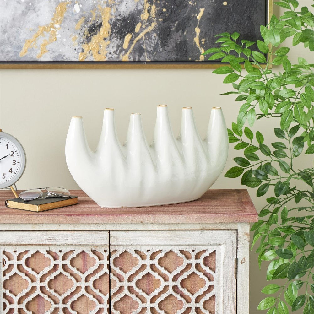 White vase on patterned cabinet, next to clock and plant.
