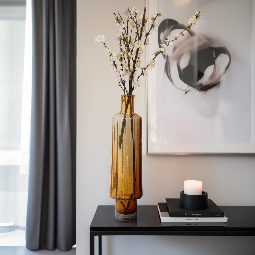 Elegant vase with flowers, candle, books, modern art, and gray curtain decor.