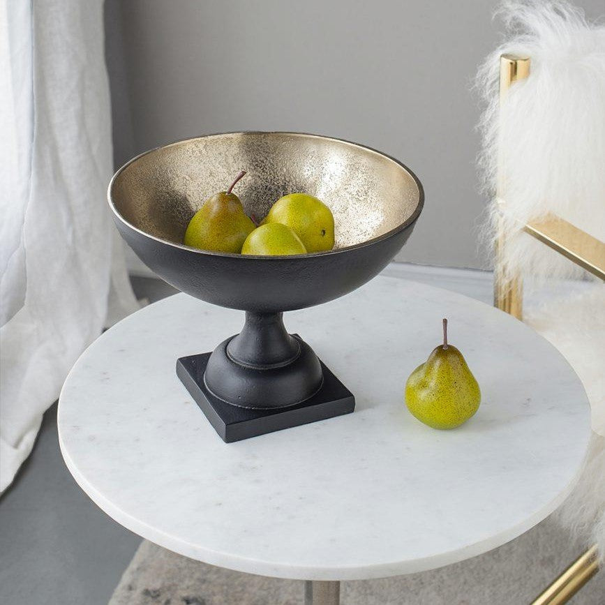 Pears in an elegant black and gold bowl on a marble table.