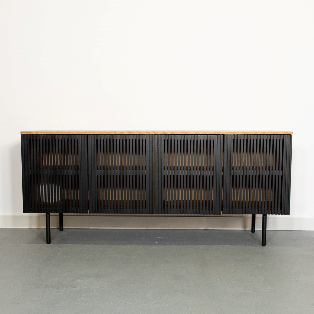 Black slatted sideboard with wooden top, standing against a white wall.