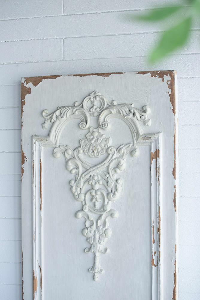 Ornate vintage white panel with peeling paint and elegant carved design.