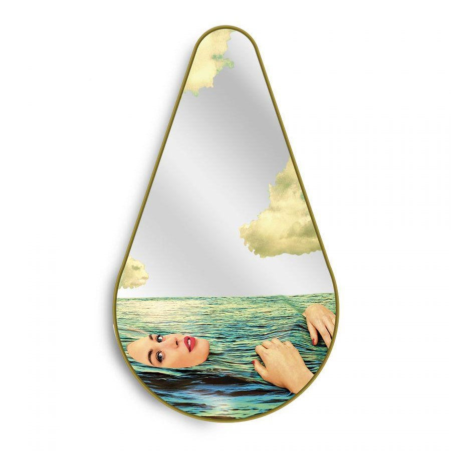 Teardrop mirror with woman swimming in ocean and sky reflection.