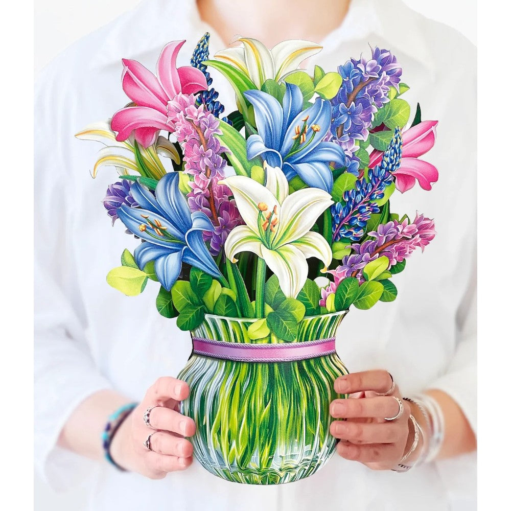 Person holding a bouquet of colorful artificial flowers in a vase.