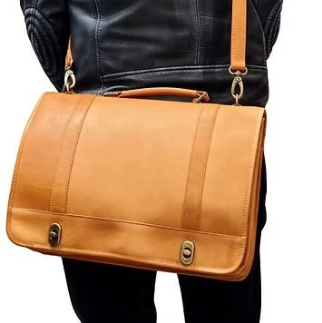 Person in a leather jacket holding a tan leather briefcase.