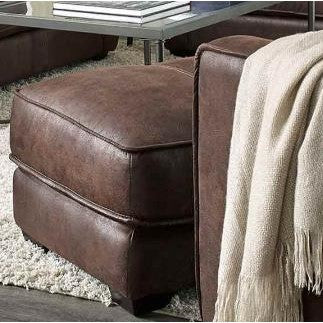 Brown leather ottoman and beige blanket in a cozy living room setting.