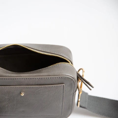 Gray leather bag with open zipper and gold ring attachments.
