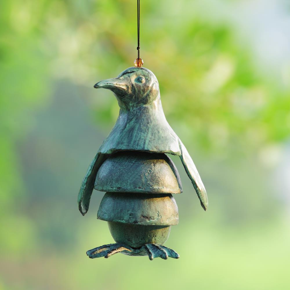Hanging bronze penguin wind chime in a garden.
