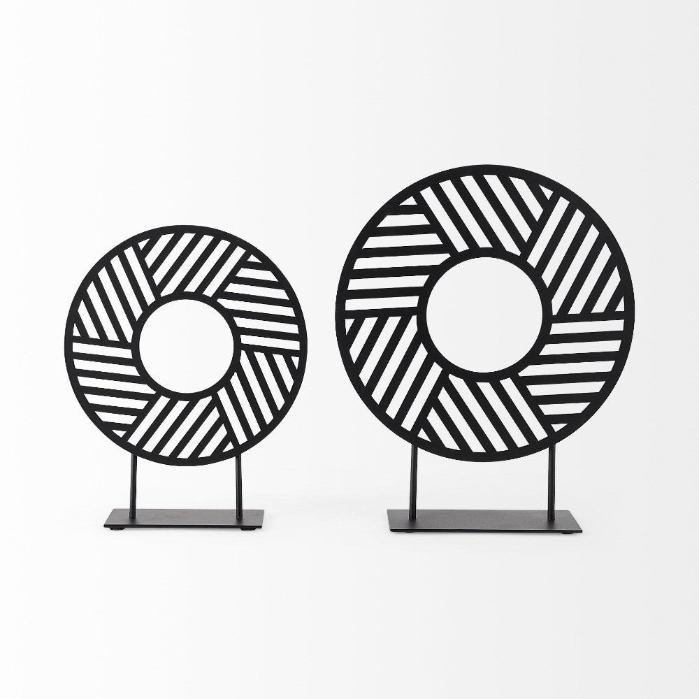 Two black geometric circular sculptures on stands.
