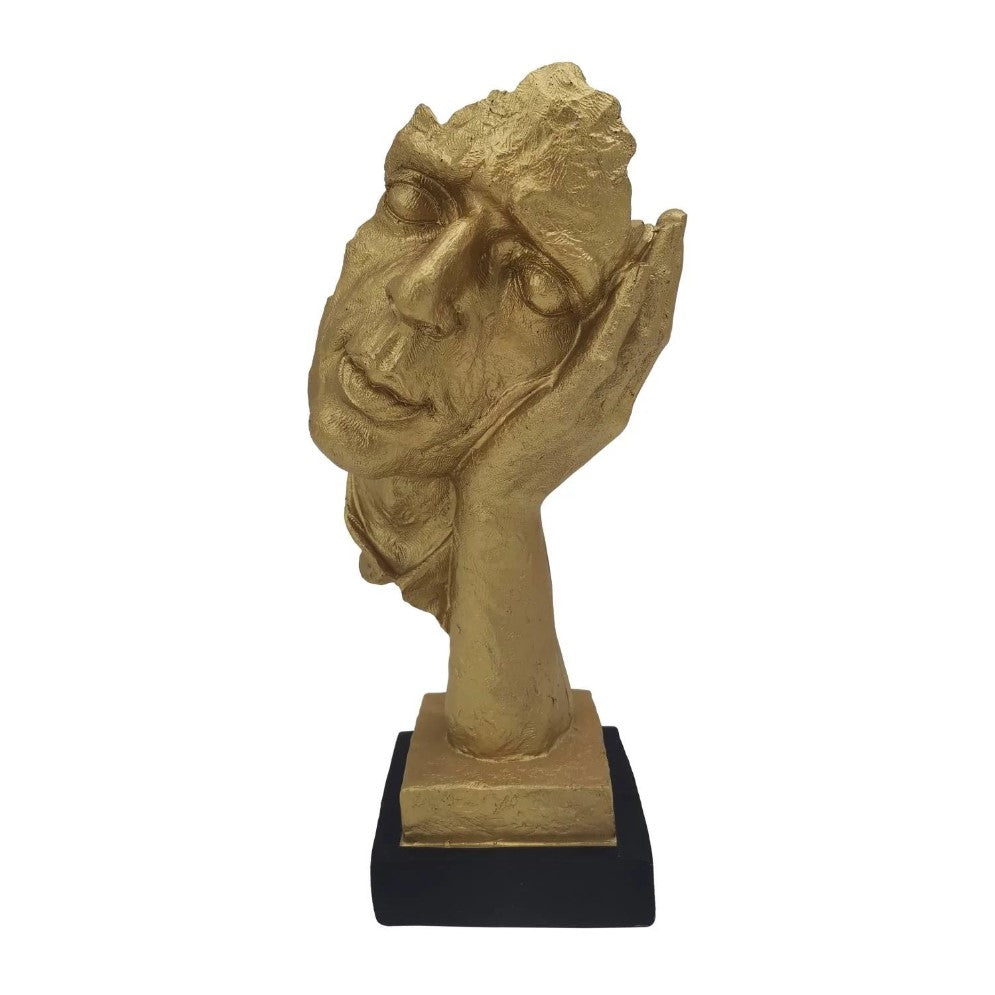 Golden face sculpture, resting on a hand, on a black base.