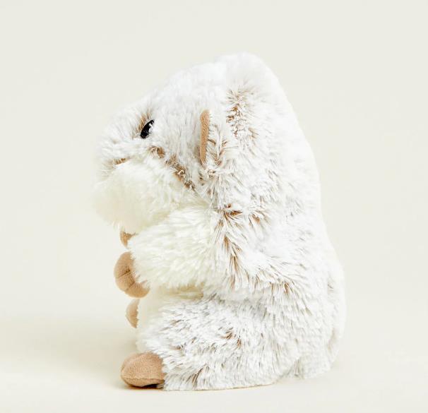 Fluffy toy hamster sitting sideways on a plain background.