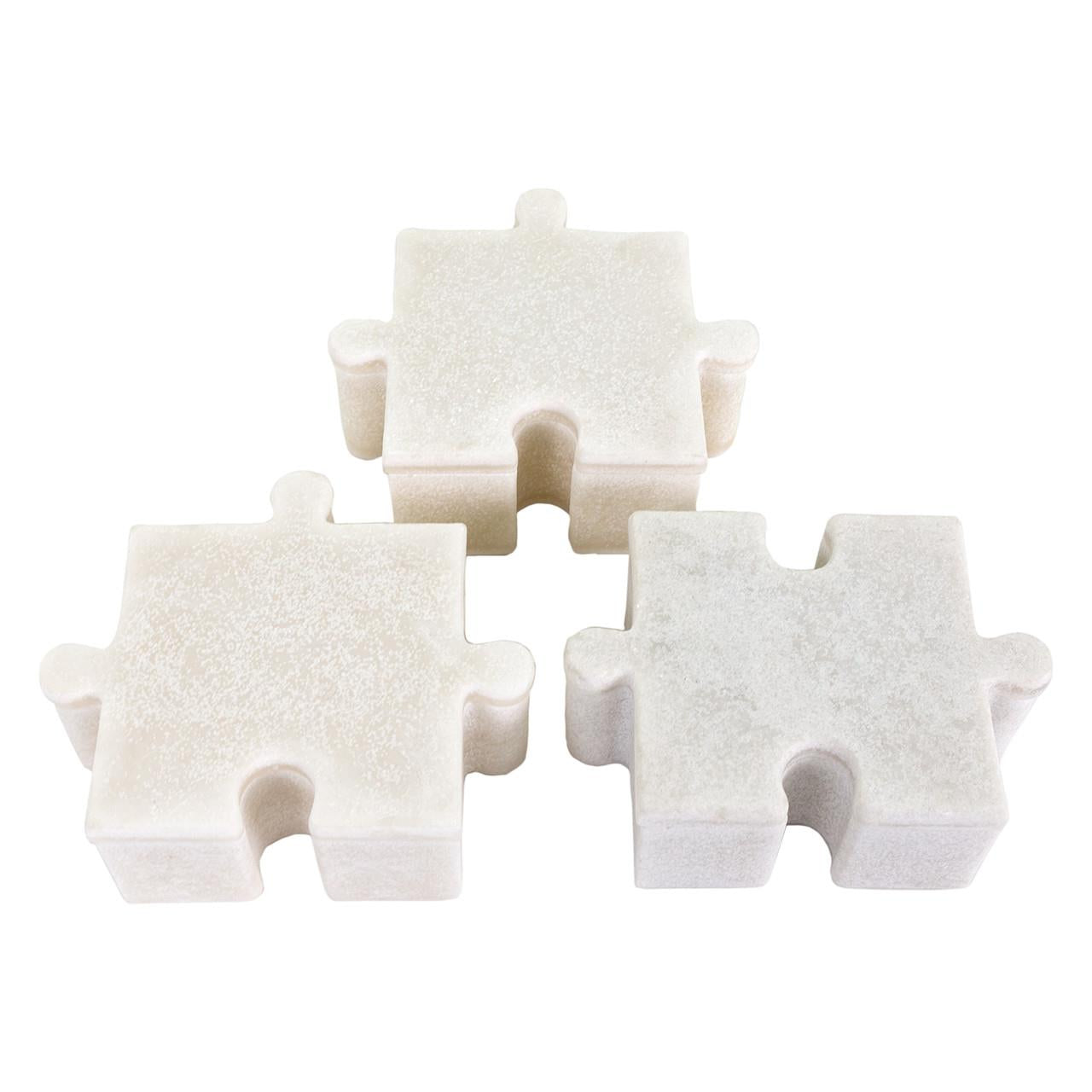 Three white puzzle piece sculptures on a white background.