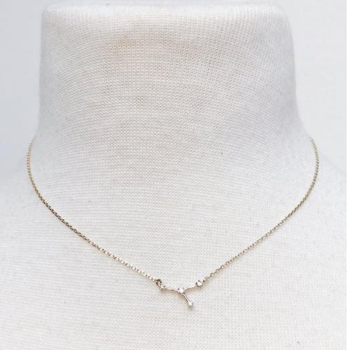 Gold chain necklace with dainty pendant on a white display.