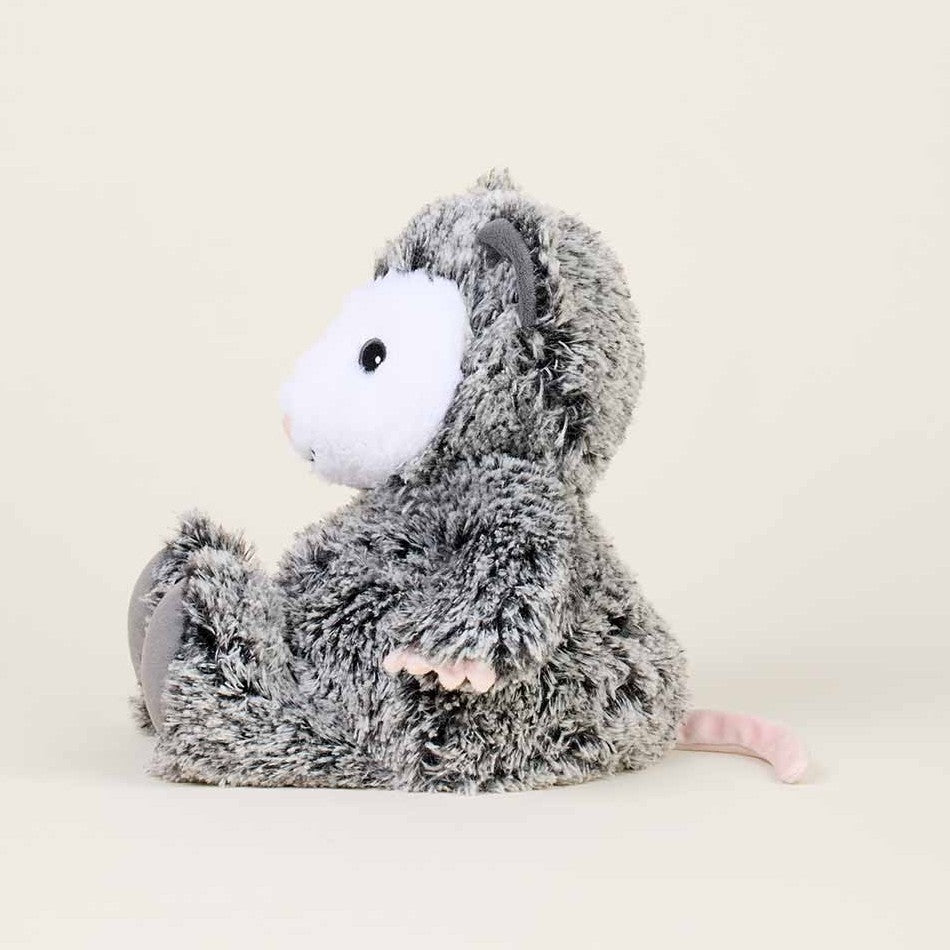 Fluffy gray stuffed animal with a white face, sitting on a light background.