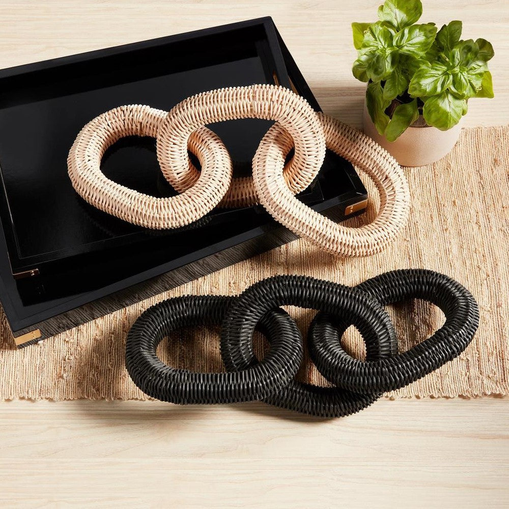 Woven chain links on black tray and mat, with a small potted plant.