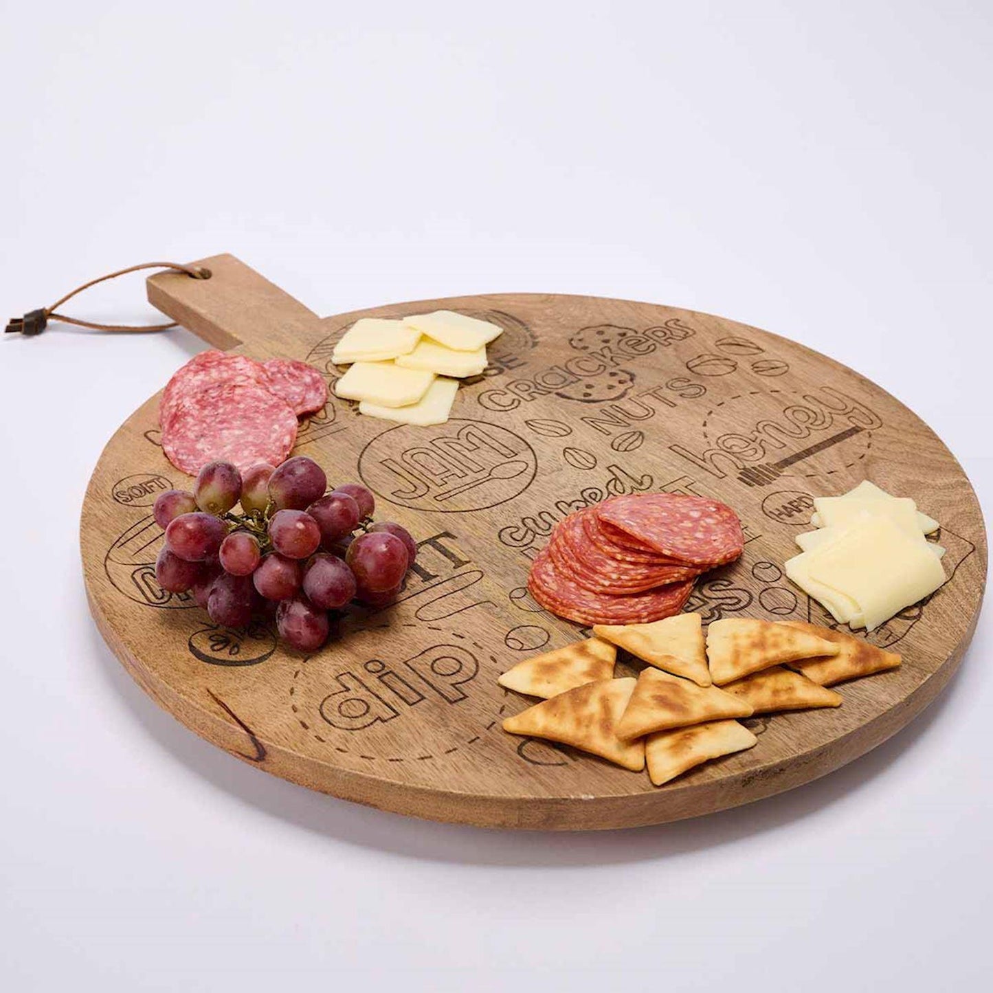 Round charcuterie board with meats, cheeses, crackers, and grapes.