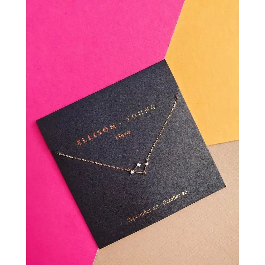 Gold Libra necklace on colorful background.