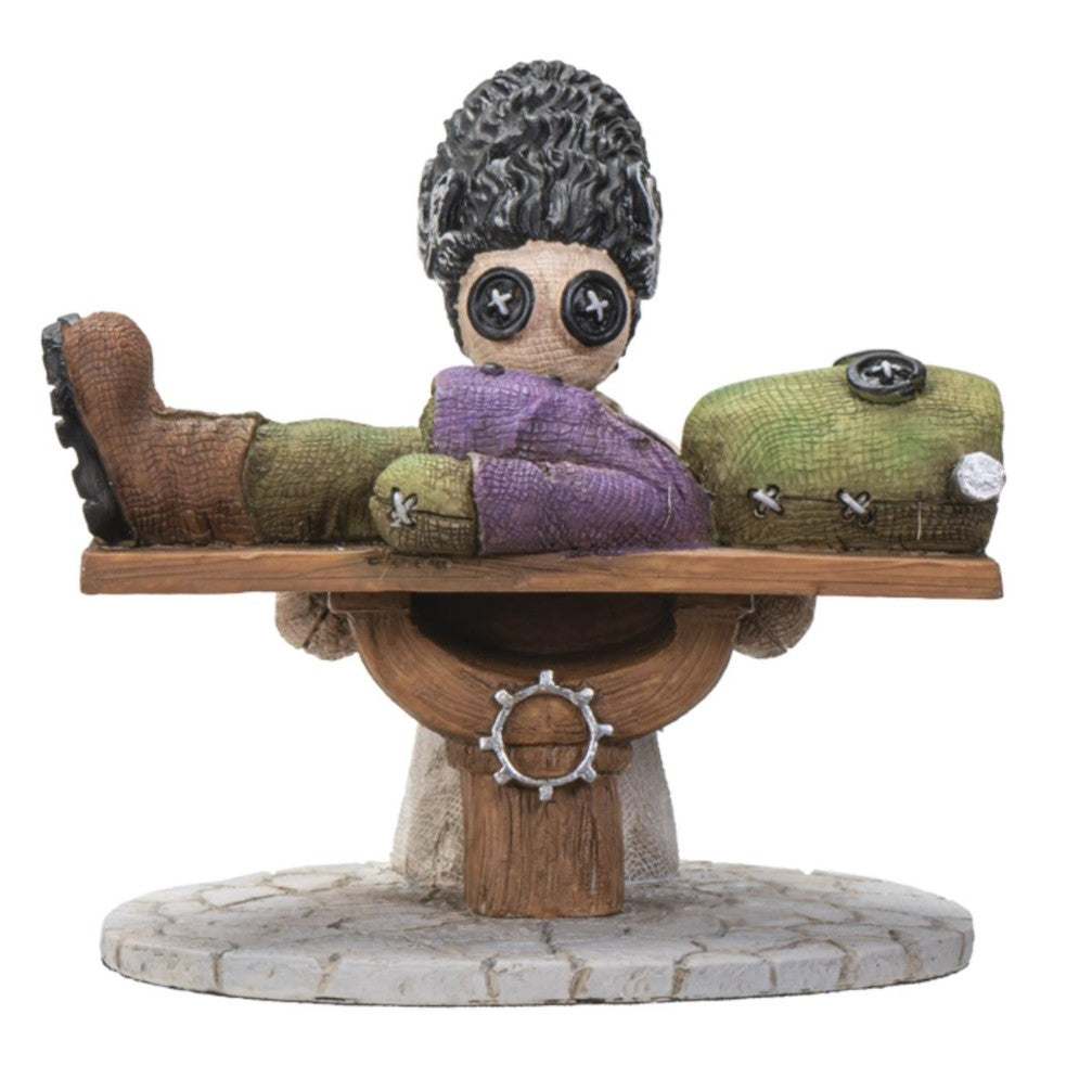 Button-eyed figure with doll on a table.
