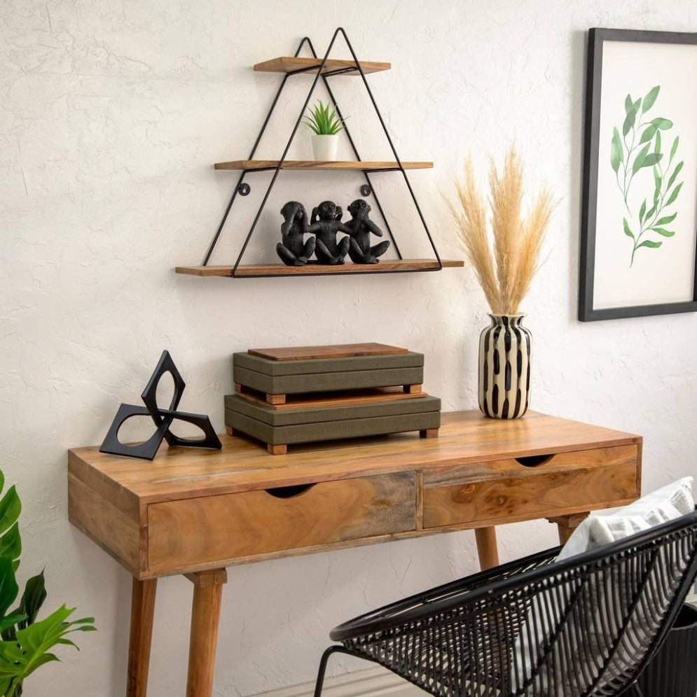 Wooden desk with decor, triangular shelves, and framed leaf art.