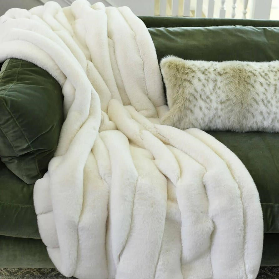 White fur blanket and pillow on green couch.